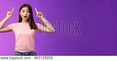 Excited Cute Surprised Asian Girl In Pink T-shirt Telling About Awesome News Pointing Raised Fingers