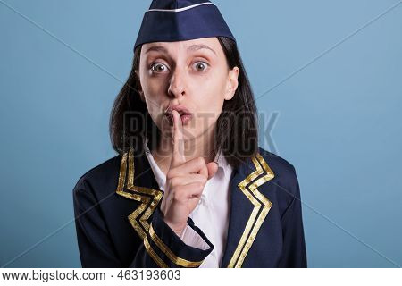 Portrait Of Stewardess Showing Silent Gesture, Looking At Camera With Forefinger On Lips. Flight Att