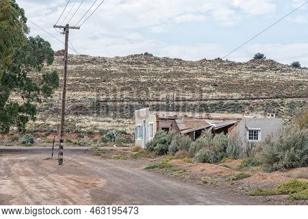 Loxton, South Africa - Sep 2, 2022: A Gravel Street Scene, With The Ruin Of A House And A Power Rout
