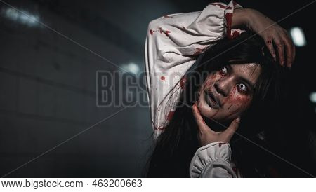 Happy Halloween Day Concept. Screaming Zombie Female Face With Blood Grabs Her Head To Twist It Off,