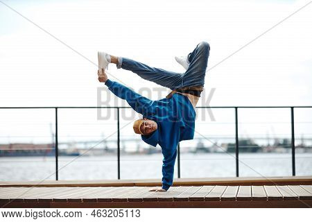 Action Shot Of Young Man Doing Breakdance Stunt Pose Outdoors Against Sky, Copy Space