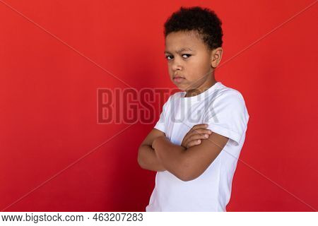 Portrait Of Resentful Preteen Boy Wearing White T-shirt Standing With Folded Arms. Multiracial Child