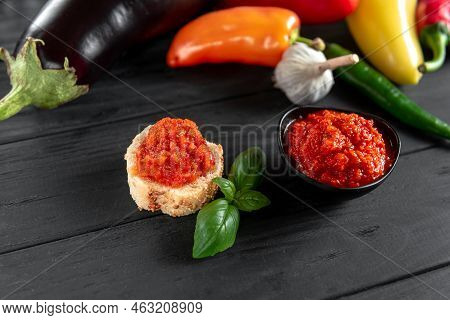 A Toast With Ajvar. Ajvar Homemade. An Appetizer Of Baked Sweet Peppers On A Wooden Background. The 