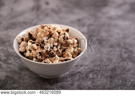 Burnt Popcorn In The Small White Bowl On Grey Ceramic
