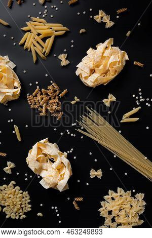 Different Types Of Uncooked Dried Pasta On The Black Background. Raw Pappardelle, Penne, Spaghetti, 