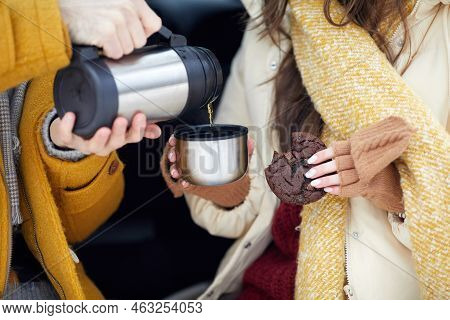 Close Up Of Couple Pouring Hot Coffee From Thermos Outdoors While Enjoying Winter Getaway