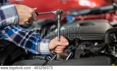 Female Auto Mechanic Unscrewing A Nut To Replace A Car Spark Plug.