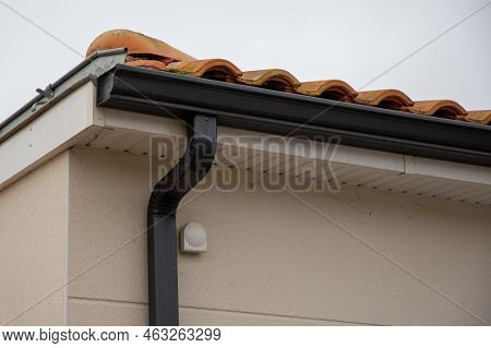 Metal Black Gutter On Home Roof Covered With Ceramic Tiles Close Up