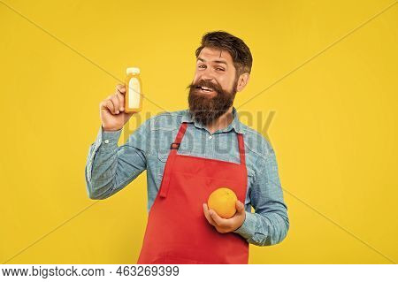 Happy Man In Apron Holding Orange And Juice Bottle Yellow Background, Barkeeper