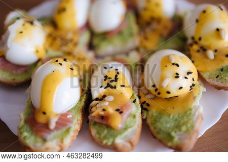 Delitious Toast With Salmon, Boiled Egg And Guacamone On A White Plat Sprinkled Pine Nuts And Black 