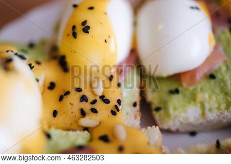 Macro Photo Of Delitious Toast With Salmon, Boiled Egg And Guacamone On A White Plat Sprinkled Pine 