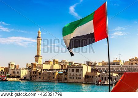 Focus On A Flag Of   United Arab Emirates Flag Against  Bay Creek And Grand Bur Dubai Masjid Mosque 