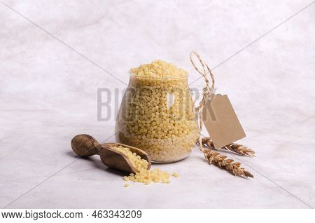 Traditional Dry Pearl Couscous In A Glass Jar On A Light Background. Selective Focus.