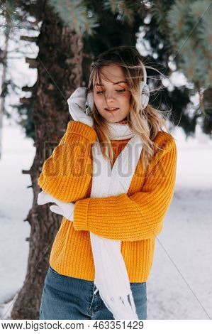 Teen Blonde In A Yellow Sweater Outside In Winter. A Teenage Girl On A Walk In Winter Clothes In A S