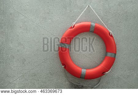 Orange Lifebuoy With Grey Strips (rescue Ring Buoy) 
Hanging On Small Gravel Wall Near Swimming Pool