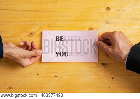 Male And Female Hands Holding Pink Paper With A Believe In Yourself Sign Written On It With Words Be