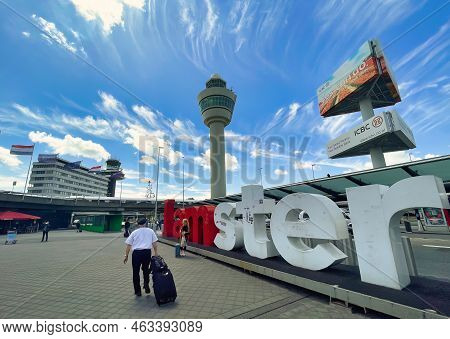 Schiphol, Netherlands - June 12 2022: Pilot Walking Outside The Terminals Of The Airport With An \