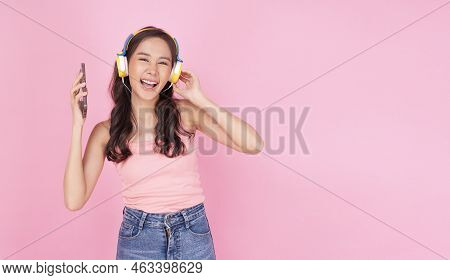 Charming Asian Woman Wear Headphones Holding Mobile Phone Listen Music Song Mood Enjoy On Pink Backg