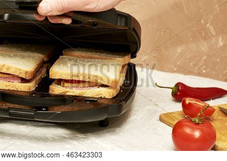 A Man Making Sandwiches In A Sandwich Maker Closes The Lid Of A Sandwich Maker