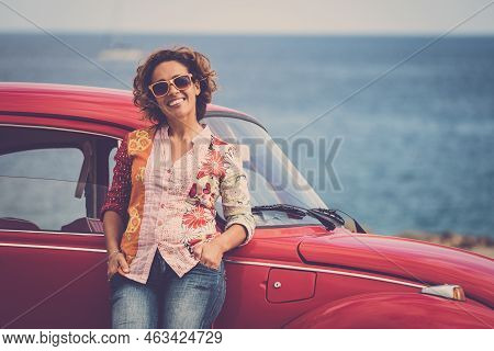 Beautiful Caucasian Middle Age Lady Driver Pose Standing With A Red Legendary Retro Vintage Car Behi