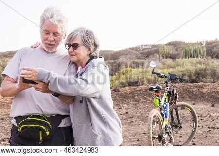 Adult Mature Caucasian Couple Smile And Enjoy The Outdoor Sport Activity With Mountain Bikes While C