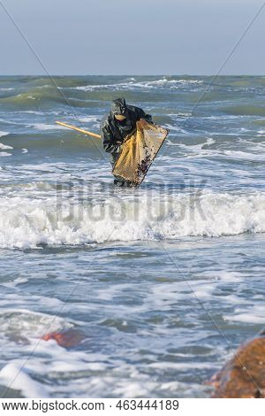 Amber Catching In The Baltic Sea. Amber Catcher Or Fisherman With Fisherman\'s Coat And Boots Into T