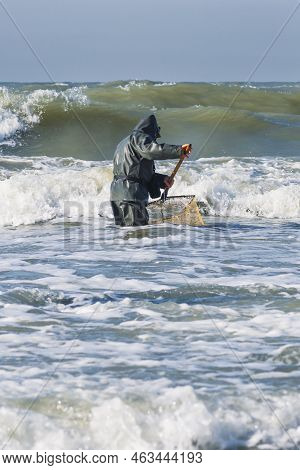 Amber Catching In The Baltic Sea. Amber Catcher Or Fisherman With Fisherman\'s Coat And Boots Into T
