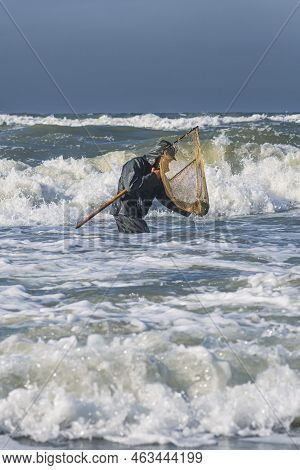 Amber Catching In The Baltic Sea. Amber Catcher Or Fisherman With Fisherman\'s Coat And Boots Into T