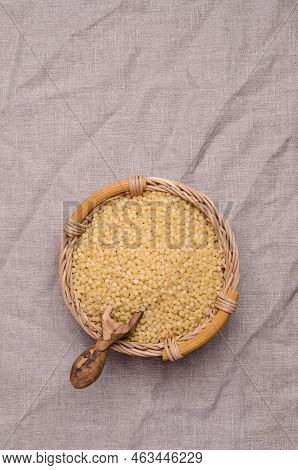 Traditional Dry Pearl Couscous In A Wicker Basket On A Textile Background. Top View.