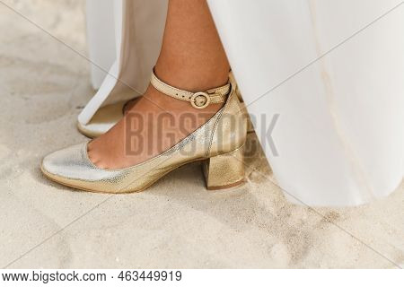 Golden Shiny Shoes Of The Bride On White Sand On The Ocean Coast