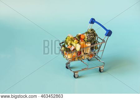 The Concept Of Using Quick-frozen Vegetables. Frozen Vegetables In A Metal Cart On A Blue Kopi Space