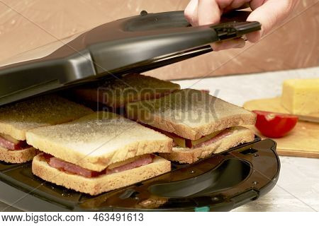 A Man Making Sandwiches In A Sandwich Maker Closes The Lid Of A Sandwich Maker