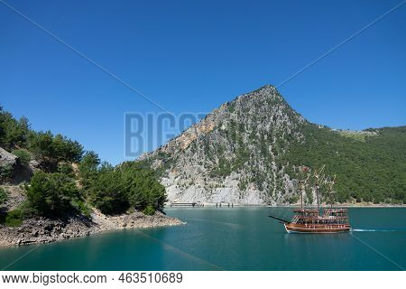 A Three-masted Tourist Yacht Floats On A Lake Among Mountain Cliffs Near The Oymapinar Dam. Green Ca
