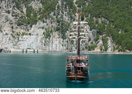 A Three-masted Tourist Yacht Floats On A Lake Among Mountain Cliffs Near The Oymapinar Dam. Green Ca