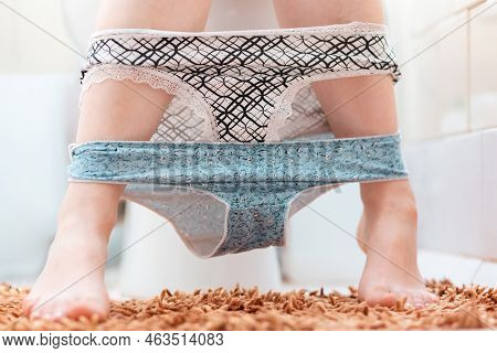 Hygiene And Cystitis. A Woman Is Sitting On The Toilet With Two Panties Removed. Close-up Of The Leg