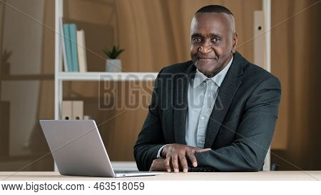 Portrait Of African Mature Senior Old Businessman Sitting In Office At Table With Laptop Nodding Hea