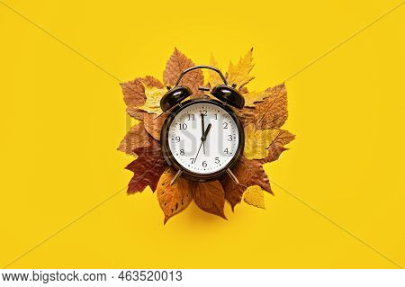 Daylight Saving Day. Fall Back. Black Alarm Clock And Autumn Leaves On Yellow Background. Daylight S