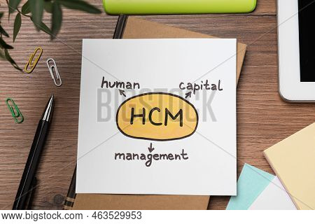 Paper With Hcm Abbreviation On Wooden Office Table, Flat Lay. Human Capital Management