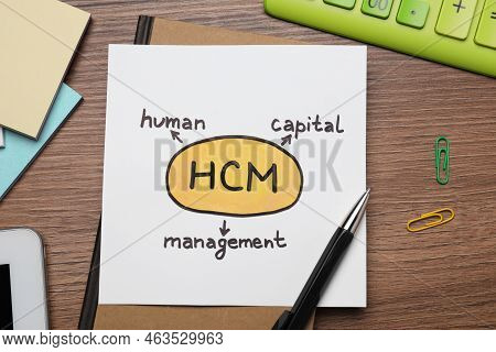 Paper With Hcm Abbreviation On Wooden Office Table, Flat Lay. Human Capital Management