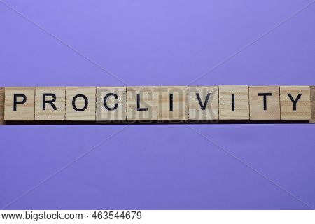 Word Proclivity Made From Wooden Gray Letters Lies On A Lilac Background