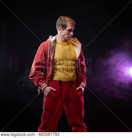 A Young Muscular Man In A Bright Outfit Poses In A Pretentious Pose, Style And Grotesque. Attractive