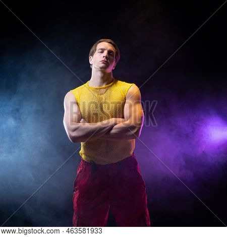 A Young Muscular Man In A Bright Outfit Poses In A Pretentious Pose, Style And Grotesque. Attractive