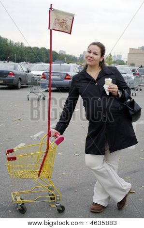 Gravid kvinna med Shopping vagn och glass.