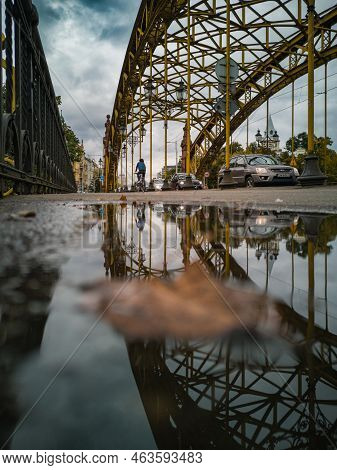 Wroclaw, Poland - September 2021: Beautiful Old Zwierzyniec Bridge Reflected In Puddle At Cloudy Day