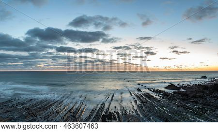 Stunning Sunset Landscape Image Of Welcome Mouth Beach In Devon England With Beautiful Rock Formatio