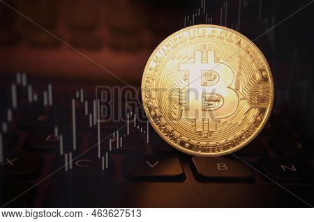Bitcoin Coin And Market Chart Graphics On Blurred Dark Computer Keyboard Background. Bitcoin Value C