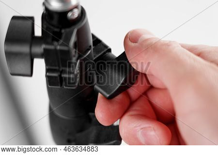 Fixing The Adjustable Detail Of The Photographic Tripod In The Studio. Turning, Tightening A Black P
