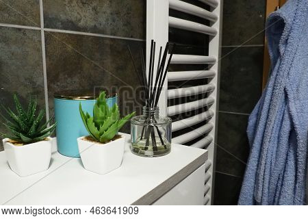 Bathroom Decor Elements. A Blue Jar Of Cream And Green Plants In Small White Pots Are On A Shelf In 