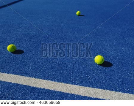 Three Balls On A Blue Paddle Tennis Court Surface