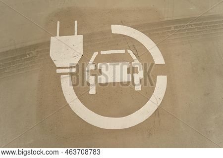 Closeup On An White Eletric Car Charging Logo , Painted On A Ground Of A Renewable Energy Parking Sp